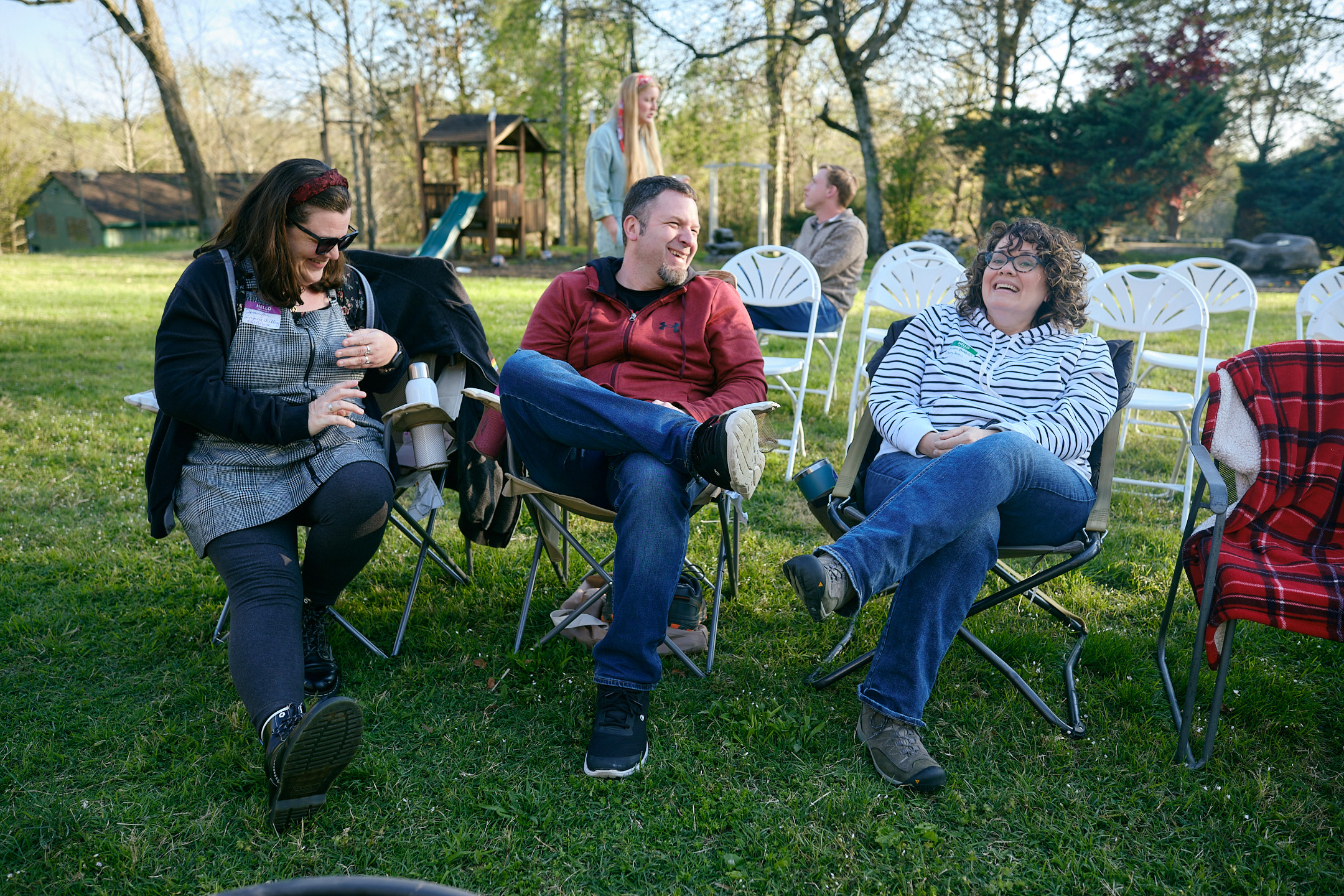 friends laughing in chairs outside in nature